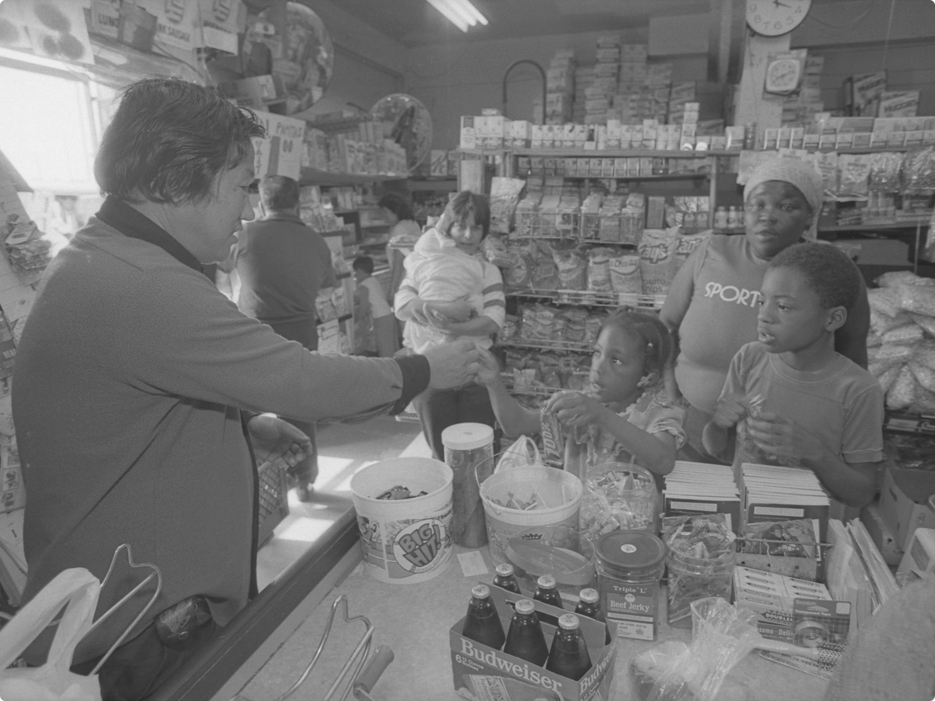 Kyu Chang Lee waiting on young customers at his grocery store on Central Avenue in Los Angeles, California, 1986.
