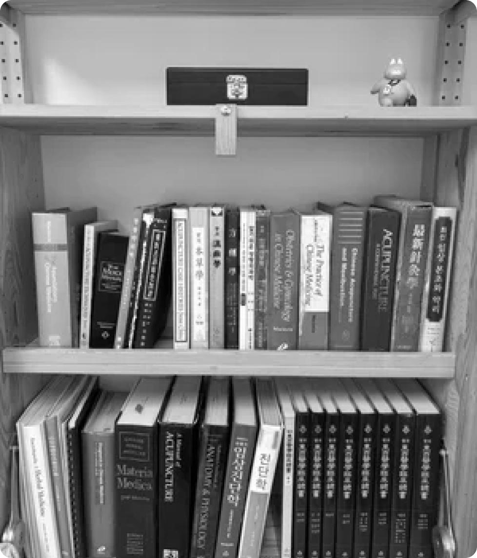 A bookshelf filled with acupuncture and traditional Chinese medicine texts in English, Korean and Chinese, including titles on Materia Medica, acupuncture anatomy and Chinese medicine.