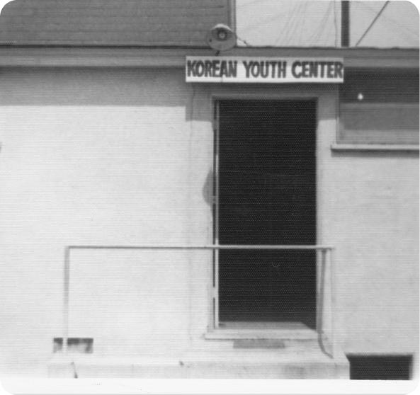 Storefront signage in Korean along a Koreatown commercial block, photographed in black and white.